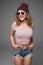 Stylish fashion portrait of trendy casual young woman in sunglasses and hat hipster in studio