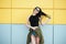 Stylish Fashion portrait of trendy cheerful casual young woman in black sunglasses posing near bright yellow urban wall. Beauty