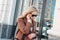 Stylish fashionable blonde woman wearing coat and sunglasses speaking on mobile phone at the street