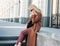 Stylish fashionable blonde woman wearing coat and sunglasses speaking on mobile phone, street style photo