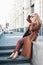 Stylish fashionable blonde woman wearing coat and sunglasses speaking on mobile phone, street style photo