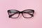 Stylish fashionable glasses on creative pink background