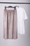 Stylish female oversize t-shirt and biege pleated skirt hanging on a rack. Fashion blog  website  social media hero header. Spring