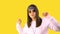 Stylish Girl in Bandana and Fashionable Glasses Dancing to Music on a Yellow Background. Young People Lifestyle Concept