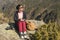 Stylish girl designer painter in the mountains sitting on a rock draws in a notepad at sunset