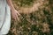 Stylish girl in linen dress gathering herbs and wildflowers in field, hand close up. Boho woman walking in countryside among grass