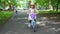 Stylish girl rides bike in Park. Happy child smiling. Little brother walking
