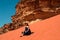 Stylish girl sitting on red dune relaxing and enjoying vacation retreat. Inspiration, travel mental health concept