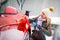 Stylish girl stands near her red electric car and waits for the car to charge. Connecting the plug of the electric