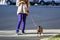 A stylish girl walks with her dog Yorkshire terrier on city street. Cute doggie on leash