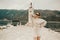 A stylish girl in a warm white suit walks on the island near the lighthouse. Travel, Montenegro