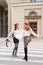 Stylish girlfriends with red berets in the style of French women smile and laugh, walking around the city, with shopping bags