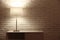 Stylish glowing night lamp on table near white brick wall. Space for text