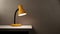 Stylish glowing yellow desk lamp on white table in room, copy space for text on gray plaster wall background