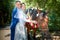 Stylish groom in a blue suit walk with the bride in a white dress in nature in the park with white horse. Wedding