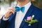 Stylish groom straightens a tie . Closeup of the clothed in blue jacket and white shirt at the park on their wedding