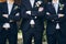 Stylish groom in suit posing with groomsmen in garden on wedding