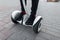 Stylish guy in jeans in sneakers in red socks rides a on white hoverboard around the city on a summer day. Closeup of male legs