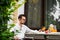 Stylish handsome man with glasses having breakfast in his country house on the veranda