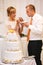 stylish happy bride and groom cutting and tasting fabulous wedding cake in a restaurant