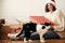 Stylish happy girl in santa hat and cozy sweater opening christmas gift box and playing with cats in decorated christmas room.