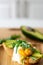 Stylish healthy breakfast of an avocado, arugula and poached egg toast on a wooden surface