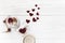 Stylish hearts in glass jar and roses on white wooden background