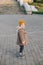 Stylish hipster baby in brown coat posing on street.