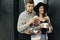 Stylish hipster couple with morning coffee smiling and relaxing on background of modern cabin with big windows in mountains. Happy