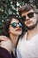 Stylish hipster couple in sunglasses smiling and making cool selfie. Happy family couple in love making self portrait and posing