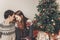 stylish hipster couple in sweaters hugging and embracing at christmas tree in cozy evening room. atmospheric moments. merry chris