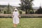 Stylish hipster girl in linen dress and hat standing at lavender field and relaxing in mountains. Back view. Bohemian woman