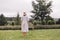 Stylish hipster girl in linen dress and hat standing at lavender field and relaxing in mountains. Back view. Bohemian woman