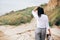 Stylish hipster girl relaxing on beach.  Happy young boho woman in white shirt walking on tropical island at sandy cliff and grass