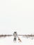 Stylish hipster girl walking with cute golden dog in snowy cold park. Woman taking walk with her dog in winter white forest. Phone