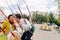 Stylish hipster newlyweds kissing while riding on high carousel in amusement park. Expressive wedding couple at carnival