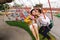 Stylish hipster newlyweds kissing while riding on high carousel in amusement park. Expressive wedding couple at carnival