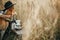 Stylish hipster traveler hugging her golden dog and brewing fresh coffee in rural countryside herbs in sunset light. Atmospheric