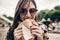 stylish hipster woman eating juicy burger. boho girl biting yummy cheeseburger, smiling at street food festival. summertime.