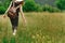 Stylish hipster woman walking in grass and holding in hand herb