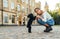 Stylish hispanic woman playing with a little black dog on the street with a serious face. Female owner on a walk with a dog on a