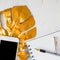 Stylish home office desk with paper notepad, white smartphone, golden pen and tropical monstera leaf