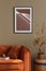 Stylish interior of living room at fancy home with design sofa, mock up poster frame, rattan basket with dried flowers, book.