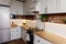 Stylish kitchen interior design. Luxury modern kitchen furniture in grey color and steel oven,fridge, sink, wooden tabletop, pots