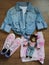 Stylish layout of clothes, top view. Jeans shirt, pink sneakers, summer skirt and a doll-cat