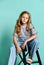 Stylish little girl child wearing summer or autumn jeans clothes sitting on a high chair in the studio.