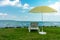 Stylish lounger plastic sunbed with yellow stripes sunshade beach umbrella on the green grass on beach at summer under open sky.
