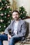 Stylish man with beard near Christmas tree