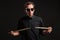 Stylish man drummer in a black shirt and sun glasses playing drums with sticks over dark background