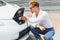 Stylish man inserts plug of the charger into the socket of electric car close-up